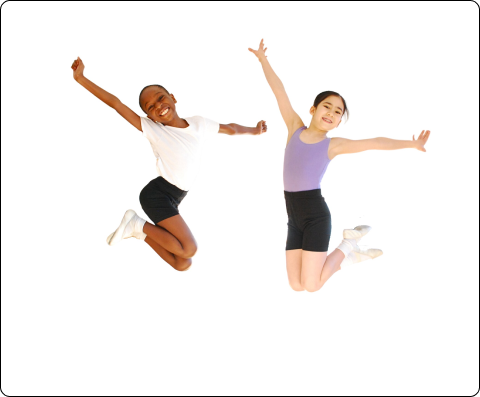 Two young students in dance uniforms jump excitedly in the air, folding in their legs and reaching arms up and out to the side.