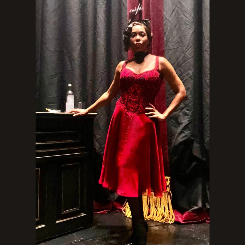 Dionne Figgins wears a red dress and feather headpiece while posing backstage. She plays Daisy Parker in the Louis Armstrong Broadway musical, "A Wonderful World."
